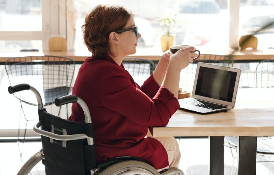 Frau im Rollstuhl arbeitet mit einem Laptop