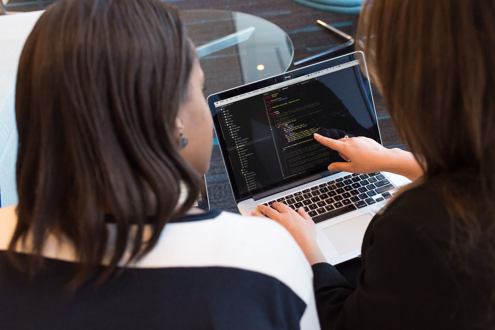 Zwei Personen arbeiten gemeinsam an Quellcode auf einem Laptop